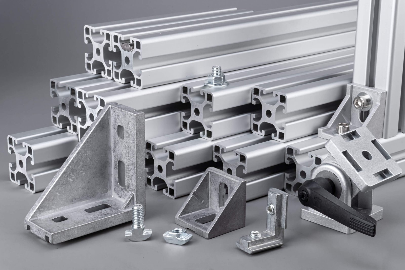 Aluminum exstrusion profile bars with accessories corner angle and screws gray background. construction industry engineering and material concept.